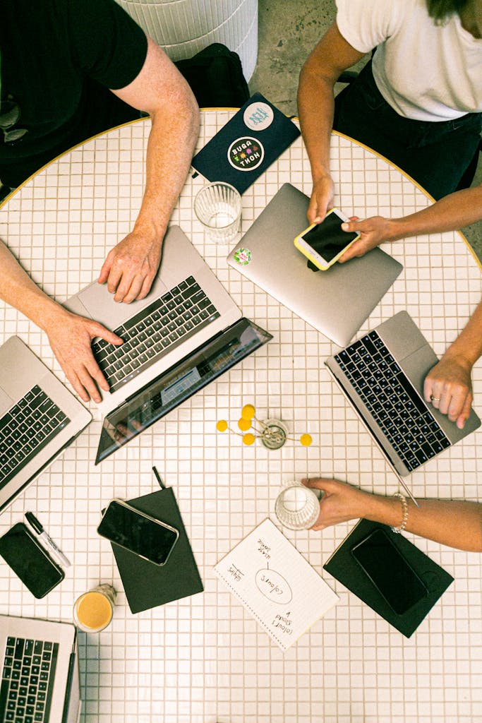 photo par canva studio Top view of a team collaborating with laptops, phones, and notes in a modern office.